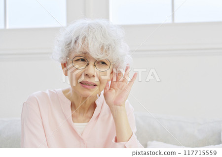 Hearing-impaired senior woman in the living room Hearing-impaired senior woman in the living room 117715559