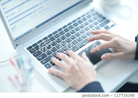 The hands of a middle-aged woman working on a computer 117716390