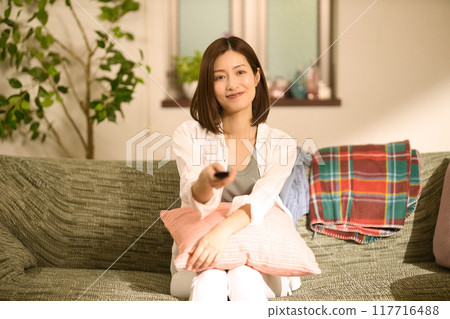 Middle-aged woman drinking coffee while relaxing on the sofa Middle-aged woman drinking coffee while relaxing on the sofa 117716488