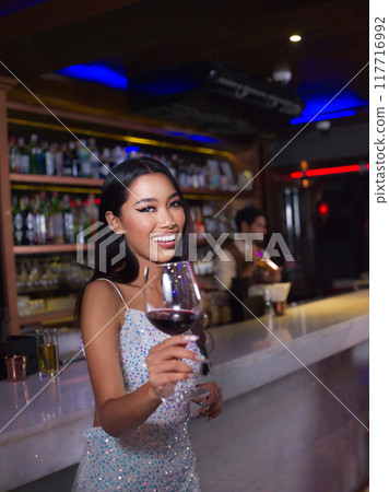 Woman is holding a glass of red wine. Bar, Restaurant, hospitality and beverage, Night club concept. 117716992