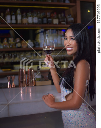 Woman is holding a glass of red wine. Bar, Restaurant, hospitality and beverage, Night club concept. 117716993