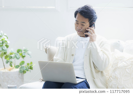Middle-aged man using a laptop in the living room Middle-aged man using a laptop in the living room 117717095