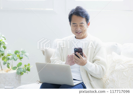 中年男子在客廳使用筆記型電腦 中年男子在客廳使用筆記型電腦 117717096