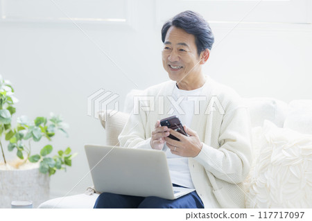 Middle-aged man using a laptop in the living room Middle-aged man using a laptop in the living room 117717097