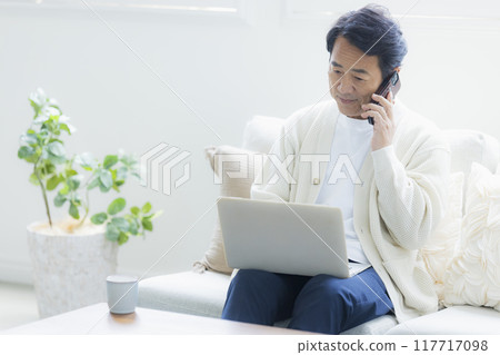 Middle-aged man using a laptop in the living room Middle-aged man using a laptop in the living room 117717098