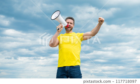 man in yellow shirt shout in megaphone on sky background. announcement man in yellow shirt shout in megaphone on sky background. announcement 117718097
