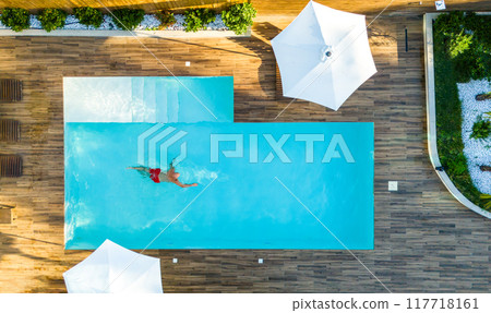 Aerial View of Man Swimming Alone in Exclusive Villa Pool. Concept of tranquility and elegance in a private retreat Aerial View of Man Swimming Alone in Exclusive Villa Pool. Concept of tranquility and elegance in a private retreat 117718161