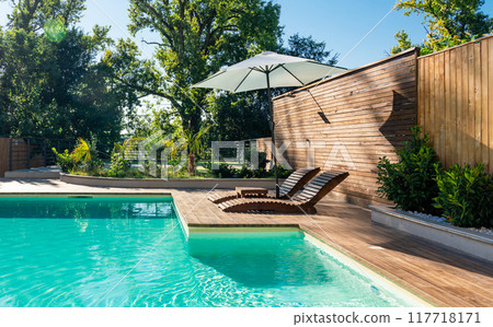 Swimming pool in modern private villa with lounge chairs, palm trees and umbrella 117718171