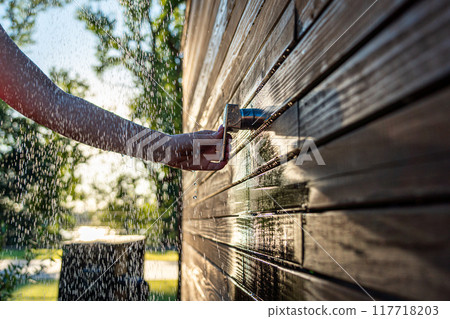 Female hand opens outdoor shower at sunset. Concept of summer fun and refreshing bath with flowing water 117718203