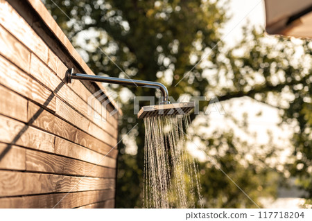Flowing water from outdoor shower at sunset near pool. Concept of relaxation and hygiene before and after swimming 117718204