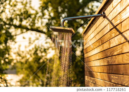 Sunset outdoor shower with flowing water by the pool for a refreshing and clean swimming experience. Concept of hygiene and relaxation Sunset outdoor shower with flowing water by the pool for a refreshing and clean swimming experience. Concept of hygiene and relaxation 117718261