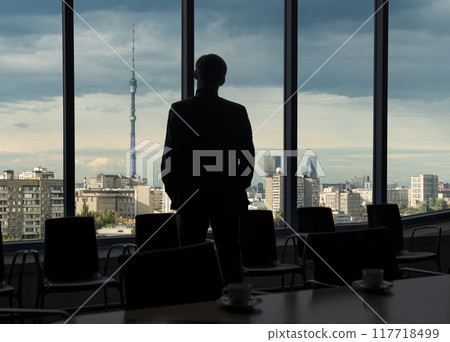 Man looking through office window on Moscow Ostankino TV tower in Russia. Panorama of the Russian city during sunset Man looking through office window on Moscow Ostankino TV tower in Russia. Panorama of the Russian city during sunset 117718499