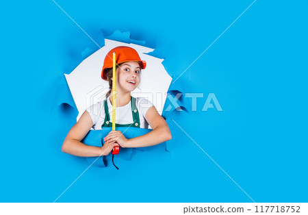 happy child hold tape measure. kid builder wear helmet. teen girl in hard hat and uniform. building and construction. concept of repair. Little girl using a measuring tape. engineer. copy space 117718752