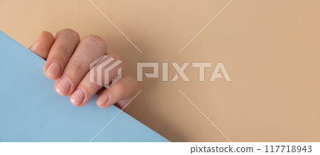 Stylish nude beige female nails on blue background. Modern trendy stylish Beautiful manicure. Mock up template copy space Cute pastel nail minimalistic design concept of beauty treatment. Gel nails 117718943