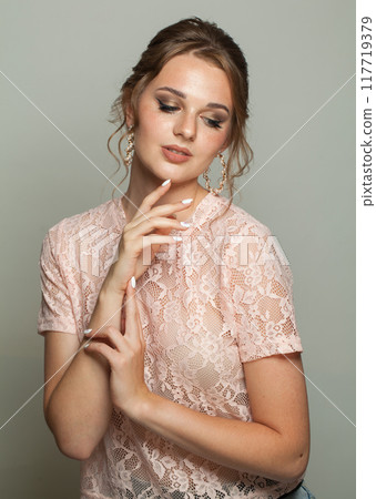 Happy glam woman fashion model with makeup and updo hairstyle on gray studio background Happy glam woman fashion model with makeup and updo hairstyle on gray studio background 117719379