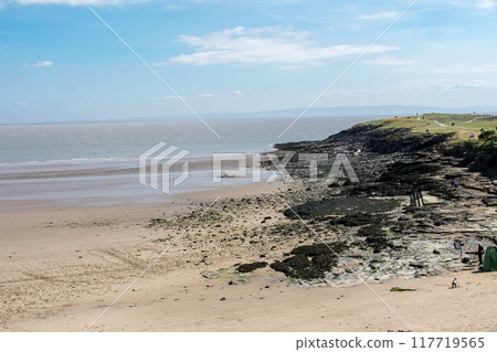 Black rock hills leading to a sandy beach in the countryside of South Wales 117719565