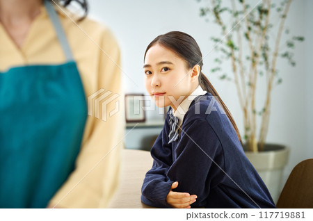 A mother in an apron and her daughter in a uniform A mother in an apron and her daughter in a uniform 117719881