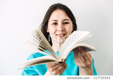 Woman smiling while holding an open book, symbolizing education, empowerment, and gender equality. 117720163