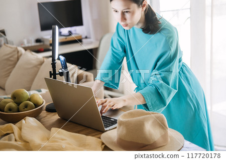 Content creator preparing to record video with ring light and laptop, digital media production, influencer workspace, online content creation, social media strategy. 117720178