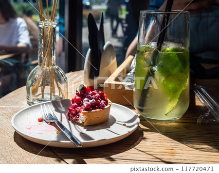 uneaten tartlet with berries on plate lit by sun 117720471