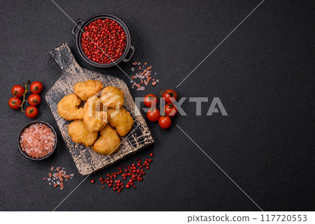 Delicious fresh crispy chicken nuggets on a dark concrete background 117720553