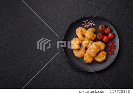 Delicious fresh crispy chicken nuggets on a dark concrete background Delicious fresh crispy chicken nuggets on a dark concrete background 117720556