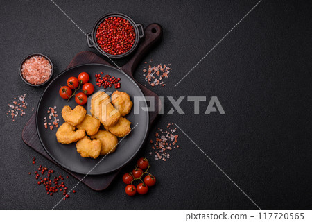 Delicious fresh crispy chicken nuggets on a dark concrete background 117720565