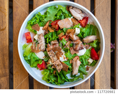 Caesar salad in bowl on wooden table 117720981