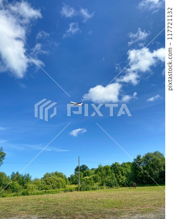 airple in blue sky over pasture on sunny day 117721132