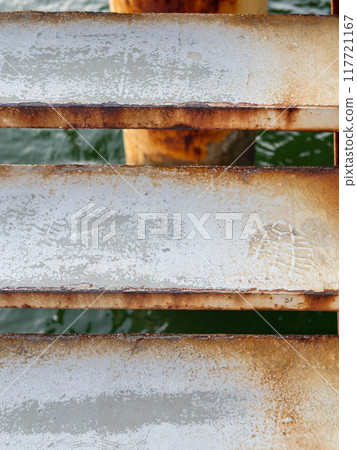 footprint on step of metal pier staircase close up 117721167