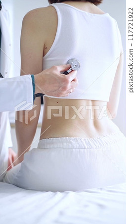 Doctor and patient. Physician is using stethoscope examining woman lungs from the back side. Medicine and health care 117721922