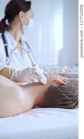 Doctor woman with white medical gloves performing neck ultrasound exam on male patient. Thyroid gland examination. Medicine concept 117722008