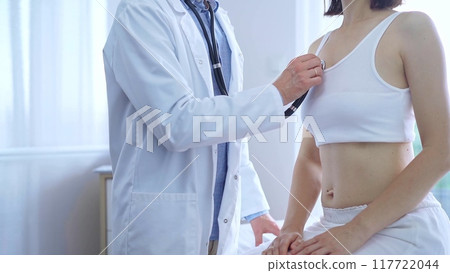 Doctor and patient. Physician is using stethoscope examining woman lungs in clinic cabinet. Medicine and health care 117722044