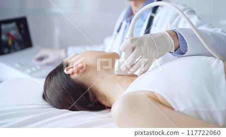 Doctor man is using ultrasound equipment on neck of female patient lying down for a medical examination. Medicine and science 117722060