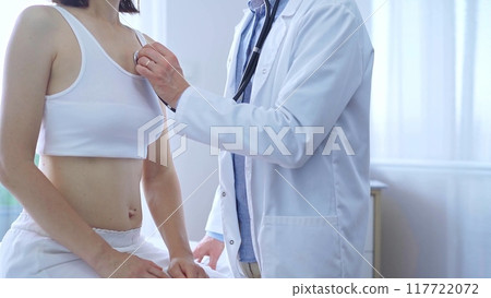 Doctor and patient. Physician is using stethoscope examining woman lungs in clinic cabinet. Medicine and health care 117722072