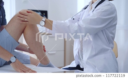 Doctor is carefully examining a patient's knee, providing personalized care and support. Medicine and orthopedic concept 117722119