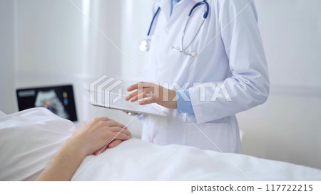 Doctor consulting patient with digital tablet in hospital room. Healthcare professional providing care Doctor consulting patient with digital tablet in hospital room. Healthcare professional providing care 117722215