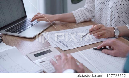 Professional female bookkeeper or auditor are working on business finances with a colleague, using calculator and laptop. Finance audit and taxes Professional female bookkeeper or auditor are working on business finances with a colleague, using calculator and laptop. Finance audit and taxes 117722222