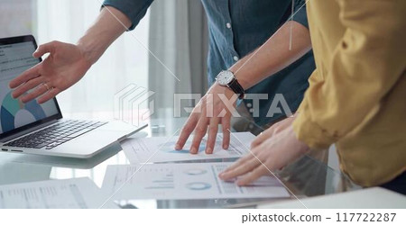 Business people, professionals analyzing financial charts and data on a desk while standing and using laptop computer in office 117722287