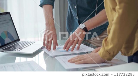 Business people, professionals analyzing financial charts and data on a desk while standing and using laptop computer in office 117722293