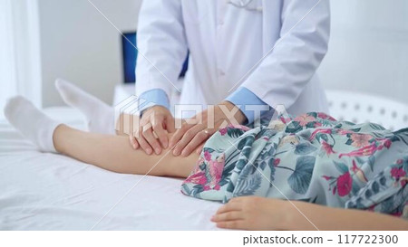 Doctor and kid patient. Orthopedist examining girl's knee in medical clinic. Medicine and health care 117722300