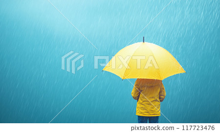 Person in a yellow raincoat holding a yellow umbrella in the rain, rear view, copy space 117723476