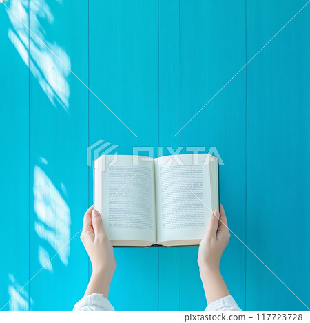 Person with open book on bright turquoise backdrop Person with open book on bright turquoise backdrop 117723728