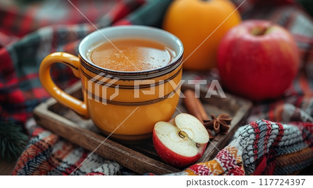 Close-up of yellow mug of hot drink with spices and cinnamon stick 117724397
