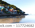 Colorful hillside village by the beach, surrounded by lush greenery and calm ocean waves 117724682