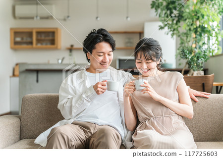 一對年輕的日本夫婦是親密的朋友，他們在自家客廳的沙發上放鬆身心 117725603