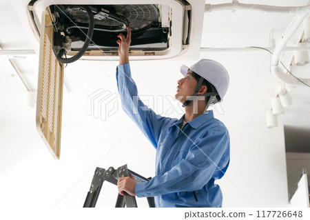 A worker inspecting an air conditioning system 117726648