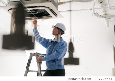 A worker inspecting an air conditioning system 117726654