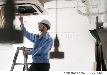 A worker inspecting an air conditioning system 117726655