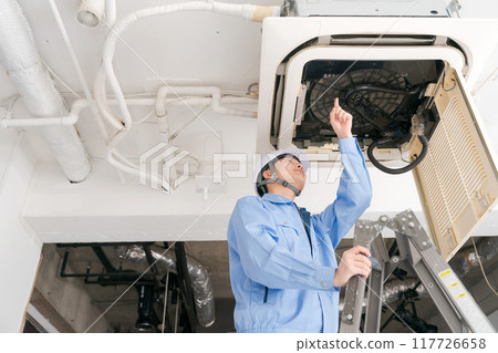 A worker inspecting an air conditioning system 117726658